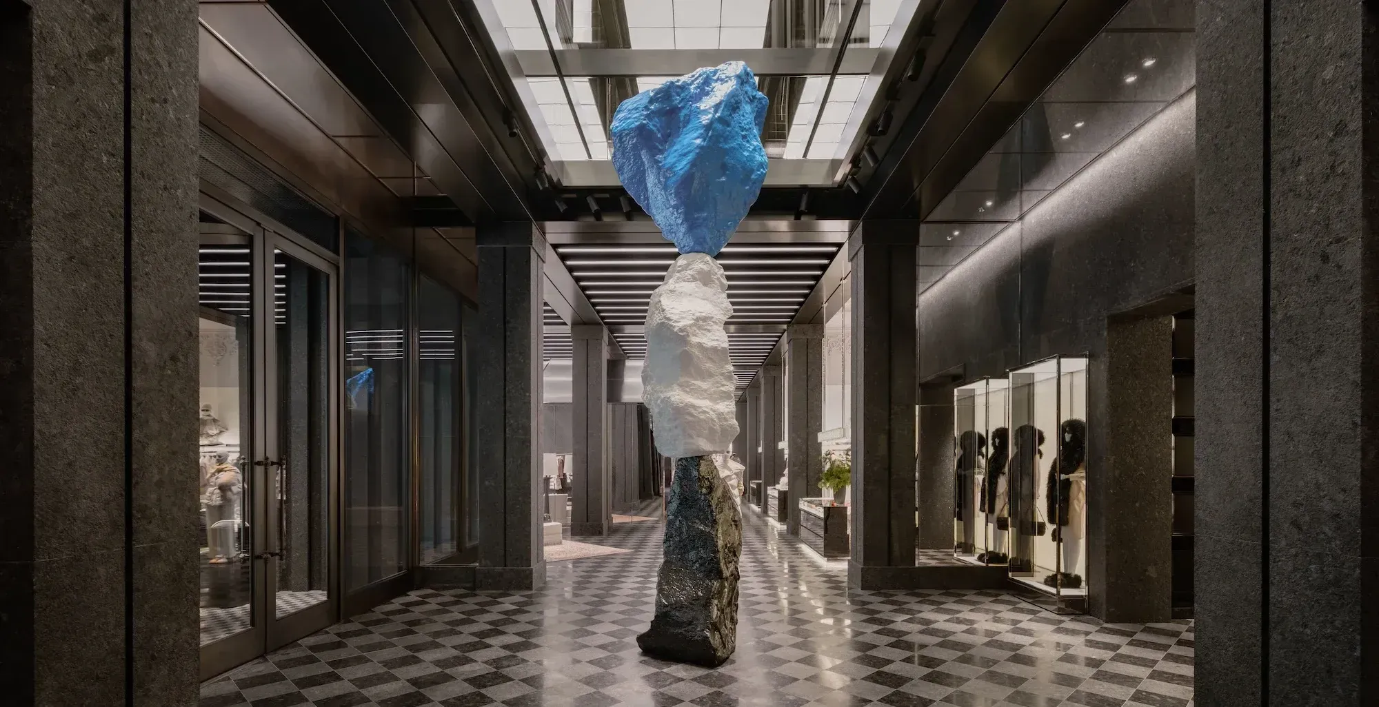 Ugo Rondinone's three-stone totem standing in the centre of a granite gallery lined with illuminated vitrines, lit from a glass ceiling above