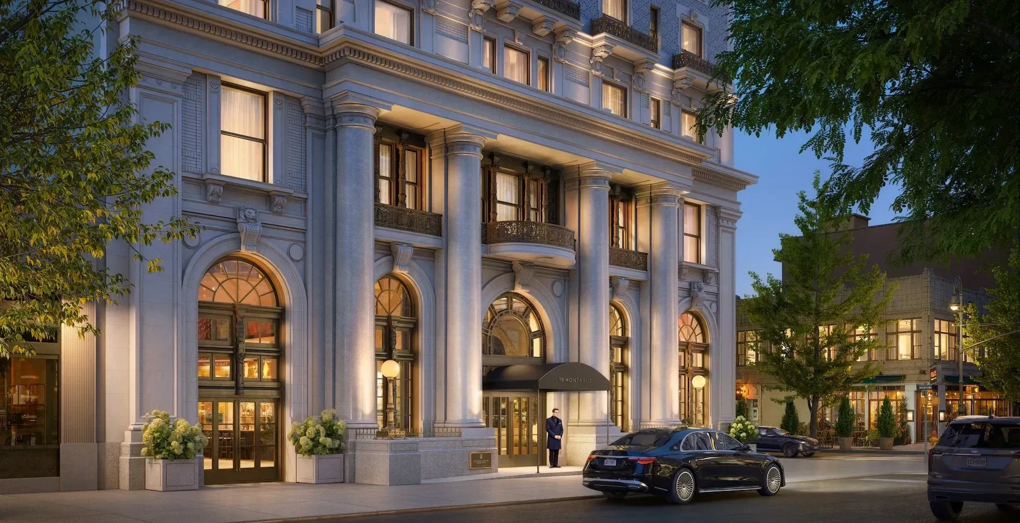 A rendering of the restored limestone and granite base of 98 Montague Street at dusk, with lit arched windows, paired columns, a black entry canopy reading 98 Montague and a doorman standing beside a waiting car